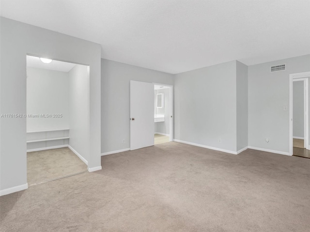 spare room featuring visible vents, baseboards, and carpet