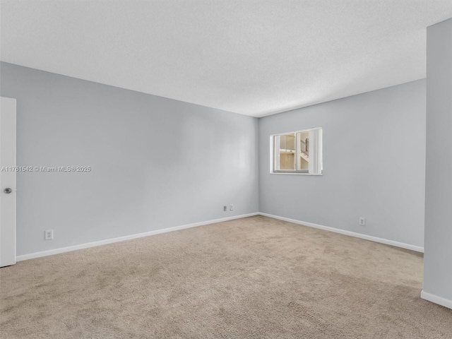 carpeted spare room featuring baseboards and a textured ceiling