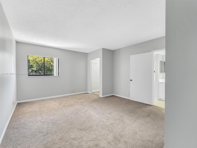 spare room with baseboards, a textured ceiling, and carpet