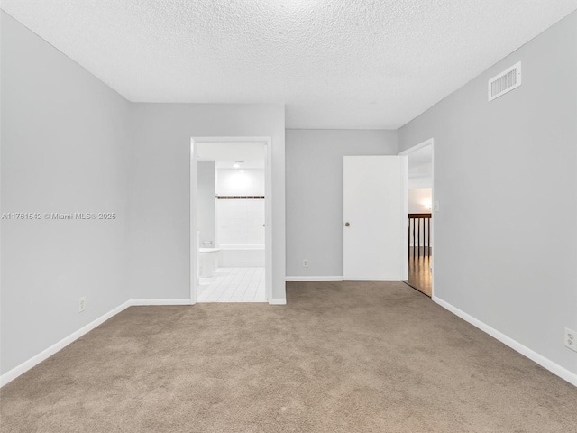 carpeted spare room with visible vents, baseboards, and a textured ceiling