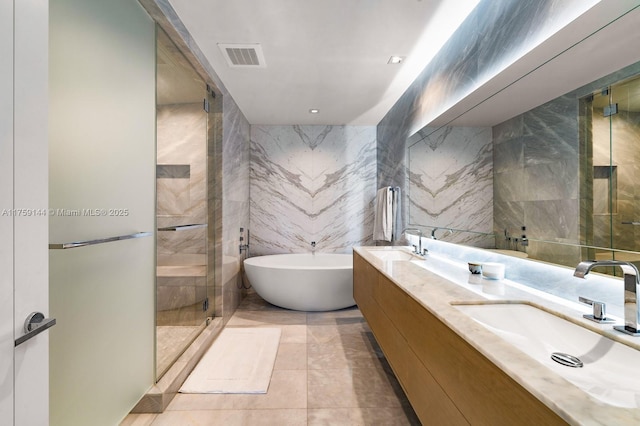 bathroom featuring visible vents, a stall shower, tile walls, and a sink