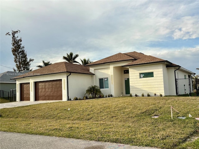 view of front of home featuring fence, a front yard, stucco siding, a garage, and driveway