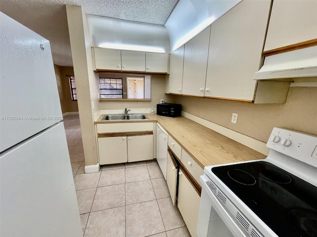 kitchen with light countertops, light tile patterned floors, white appliances, a textured ceiling, and a sink