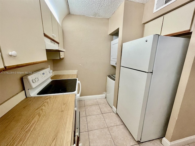 kitchen featuring white appliances, light tile patterned floors, baseboards, stacked washer and clothes dryer, and under cabinet range hood