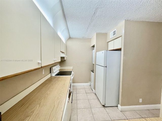 kitchen featuring visible vents, washer / dryer, light tile patterned flooring, white cabinets, and white appliances