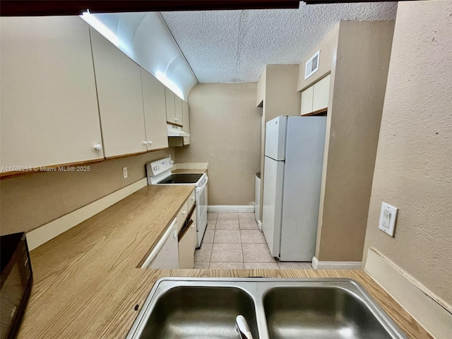 kitchen with visible vents, a sink, a textured ceiling, white appliances, and light tile patterned flooring