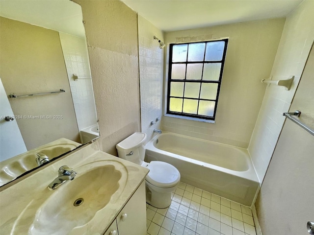 bathroom with tile patterned flooring, shower / washtub combination, toilet, a textured wall, and vanity