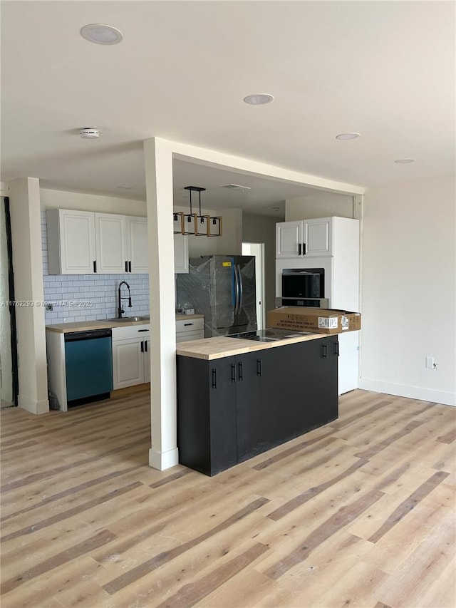 kitchen with light wood-style flooring, a sink, black appliances, white cabinets, and backsplash