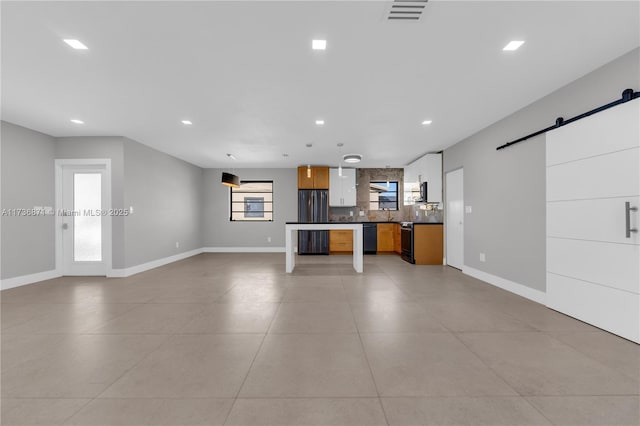 kitchen featuring dark countertops, recessed lighting, black appliances, a barn door, and open floor plan