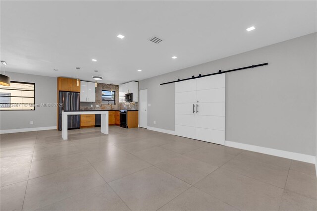 kitchen with visible vents, stainless steel appliances, decorative backsplash, a barn door, and open floor plan