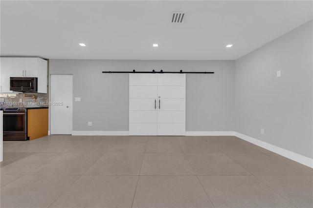 interior space with a barn door, visible vents, baseboards, and light tile patterned flooring