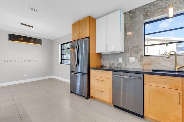 kitchen with a healthy amount of sunlight, a sink, stainless steel appliances, dark countertops, and tasteful backsplash