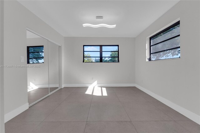 unfurnished bedroom with tile patterned floors, a closet, and baseboards