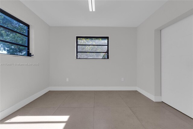 tiled spare room featuring baseboards