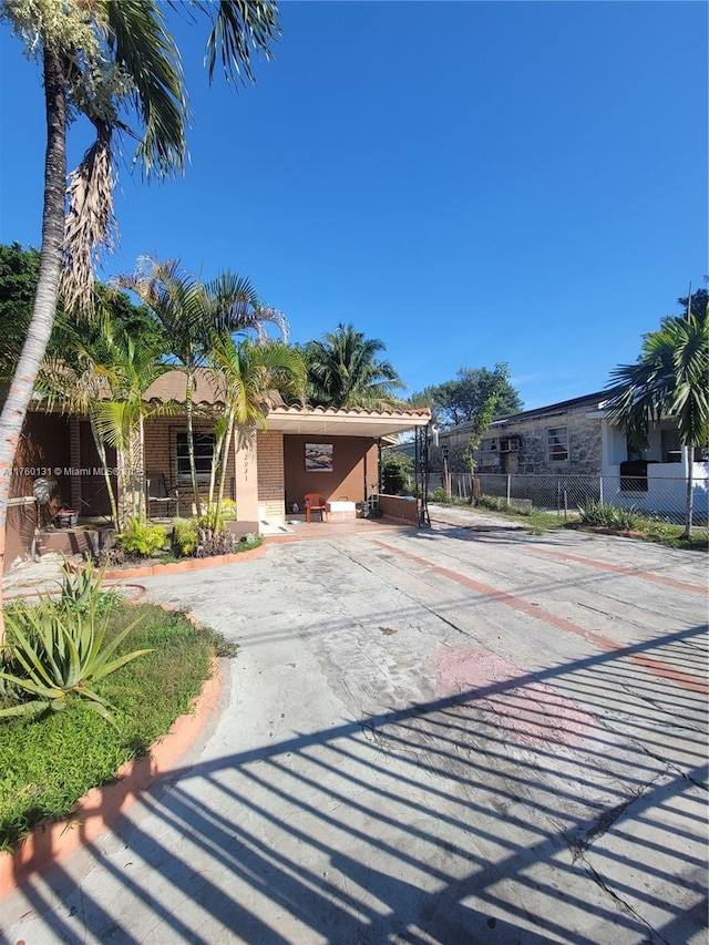 view of front of home featuring brick siding, driveway, and fence