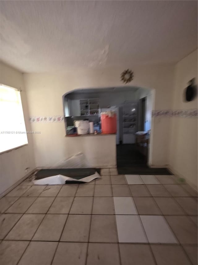 interior space featuring light tile patterned flooring and a textured ceiling