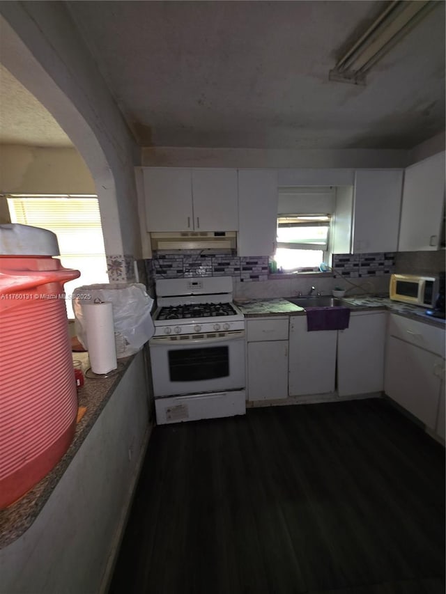 kitchen with under cabinet range hood, dark wood finished floors, white appliances, and white cabinets