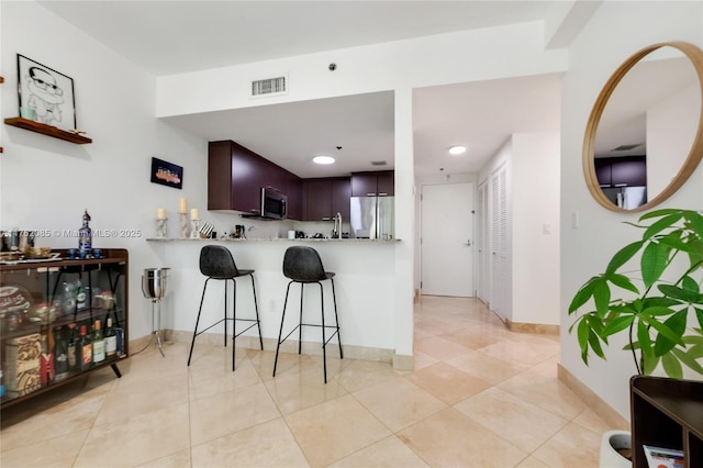 kitchen with visible vents, stainless steel appliances, a peninsula, a breakfast bar area, and light countertops