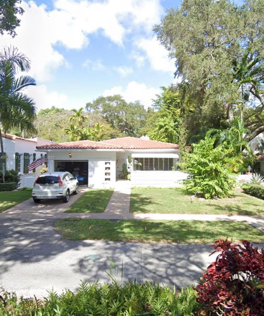 view of front of home featuring a tile roof, an attached garage, a front yard, and driveway