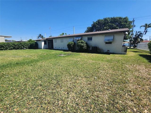 back of property with central air condition unit and a yard