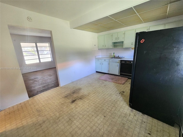 kitchen with a sink, light floors, light countertops, black appliances, and open shelves