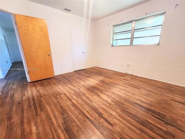 unfurnished bedroom with hardwood / wood-style flooring and visible vents