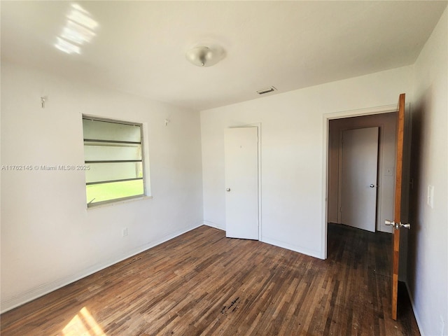 unfurnished room featuring wood finished floors, visible vents, and baseboards