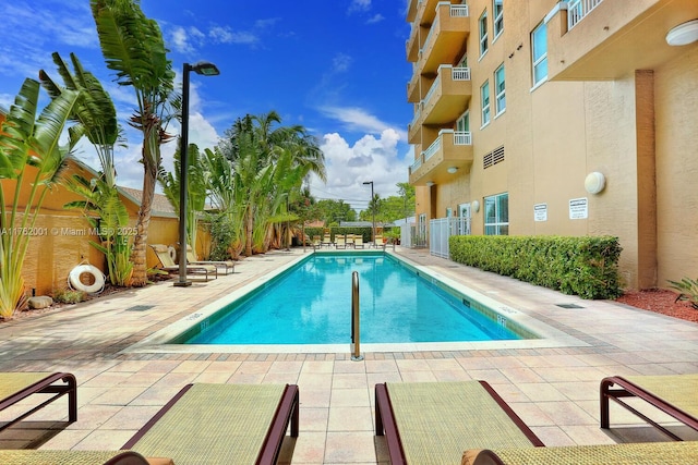 pool with a patio and fence