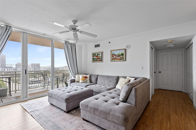 living area featuring visible vents, a city view, wood finished floors, floor to ceiling windows, and crown molding