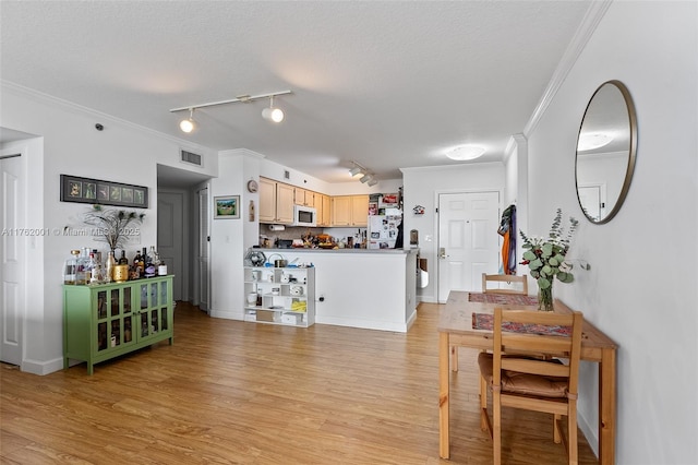 interior space featuring a textured ceiling, light wood-style flooring, visible vents, and ornamental molding