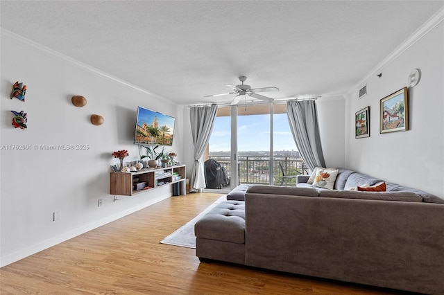 living area featuring ornamental molding, a textured ceiling, wood finished floors, a wall of windows, and baseboards