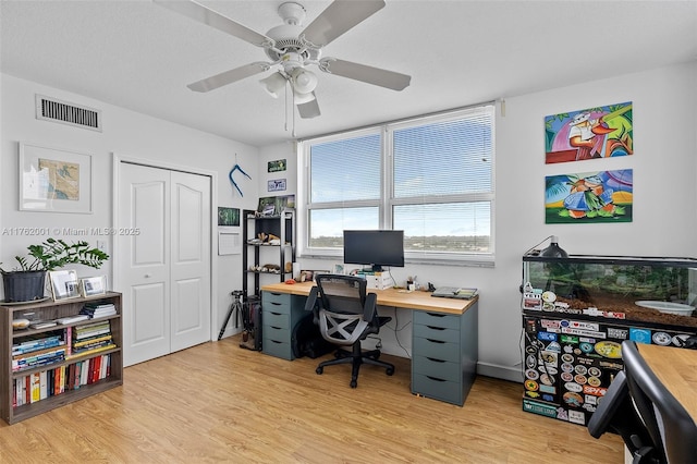 office area with visible vents, light wood-type flooring, and a ceiling fan