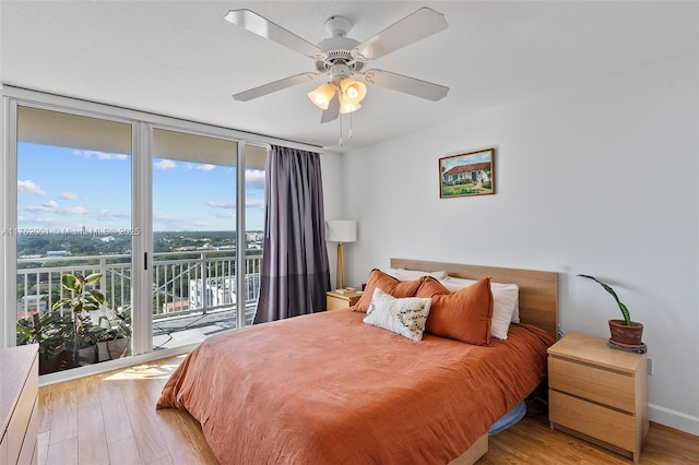 bedroom with access to exterior, light wood-style flooring, baseboards, and expansive windows