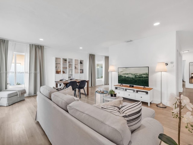 living area with recessed lighting, visible vents, and light wood finished floors