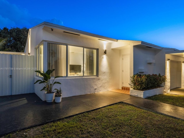 view of front of home with stucco siding and fence