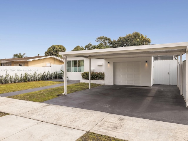 view of front of house with stucco siding, driveway, fence, a front yard, and a garage