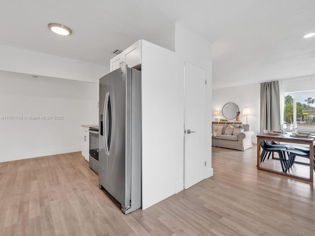 kitchen featuring baseboards, light wood-style floors, appliances with stainless steel finishes, and white cabinets