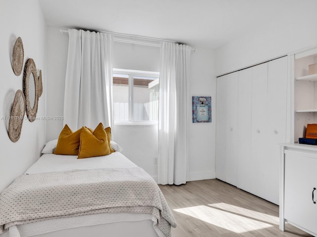 bedroom with light wood finished floors and a closet