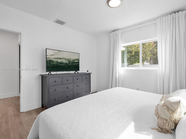 bedroom with visible vents, baseboards, and wood finished floors