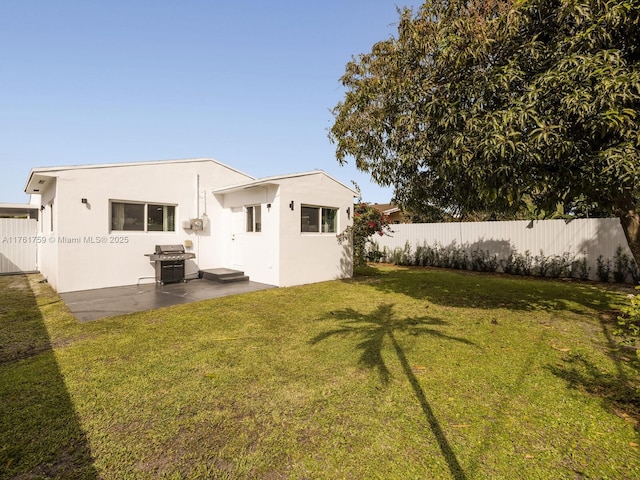 back of property featuring a patio area, fence, a lawn, and stucco siding