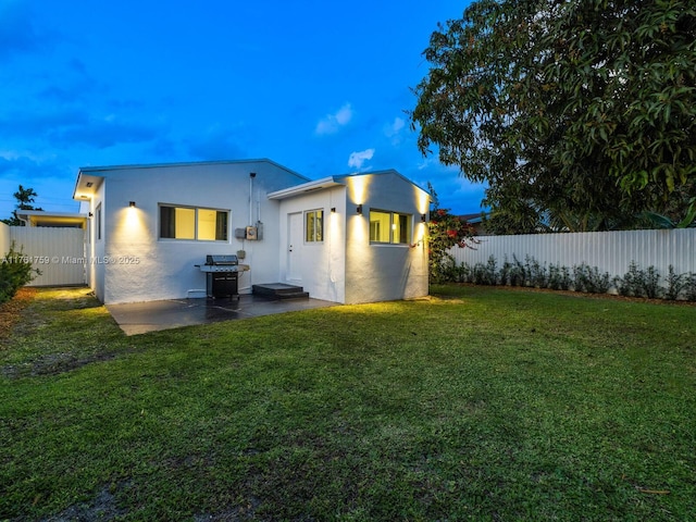 back of property with a patio area, a lawn, a fenced backyard, and stucco siding