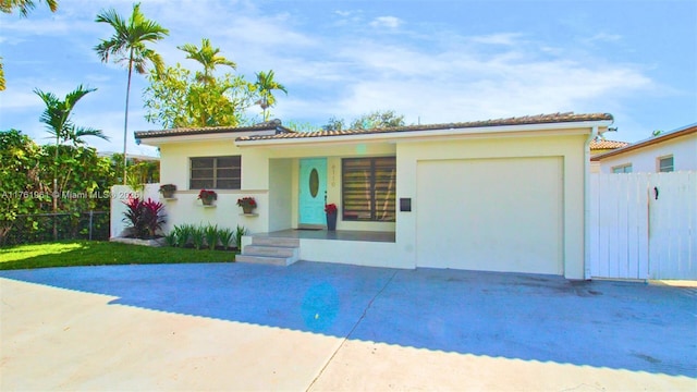 view of front of home with stucco siding, concrete driveway, an attached garage, and fence