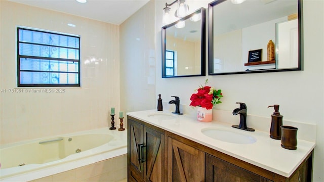 bathroom with double vanity, a tub with jets, and a sink