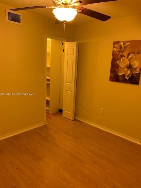 empty room with visible vents, light wood-style flooring, baseboards, and ceiling fan