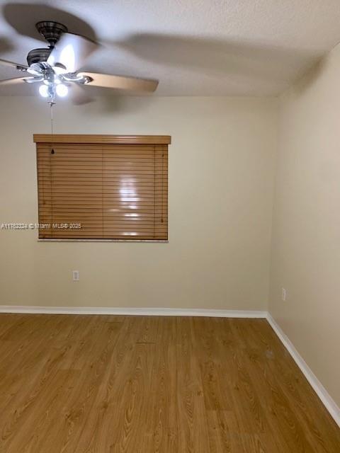 unfurnished room with wood finished floors, baseboards, and ceiling fan