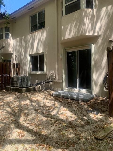 back of property with stucco siding and central AC unit