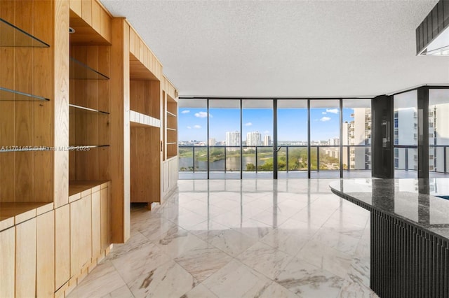 spare room with a wealth of natural light, a view of city, marble finish floor, expansive windows, and a textured ceiling