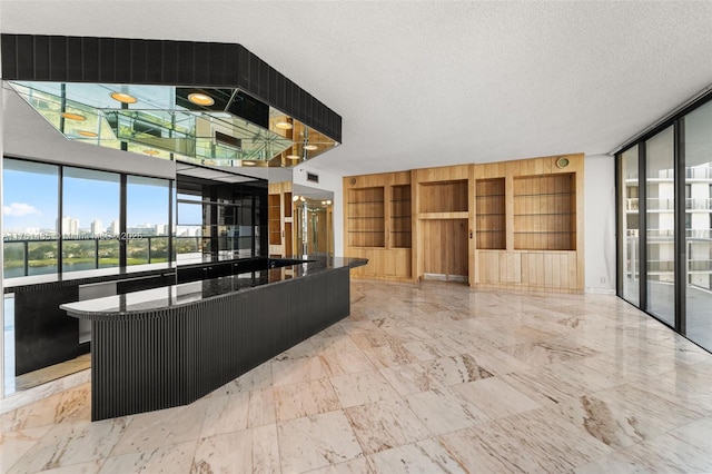 interior space featuring a view of city, built in shelves, marble finish floor, and a textured ceiling