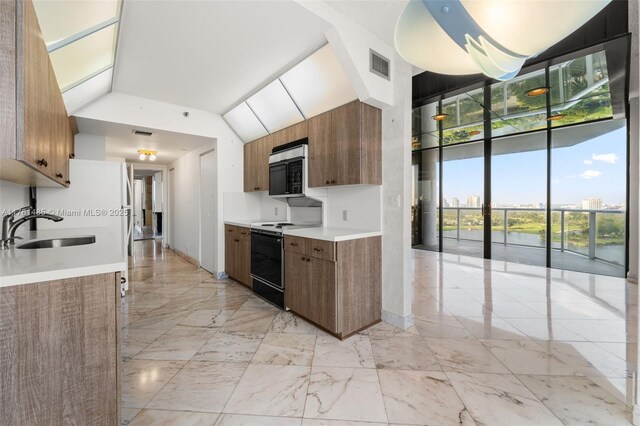 kitchen featuring stainless steel microwave, visible vents, brown cabinets, electric stove, and a sink