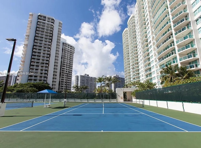 view of tennis court with a view of city and fence